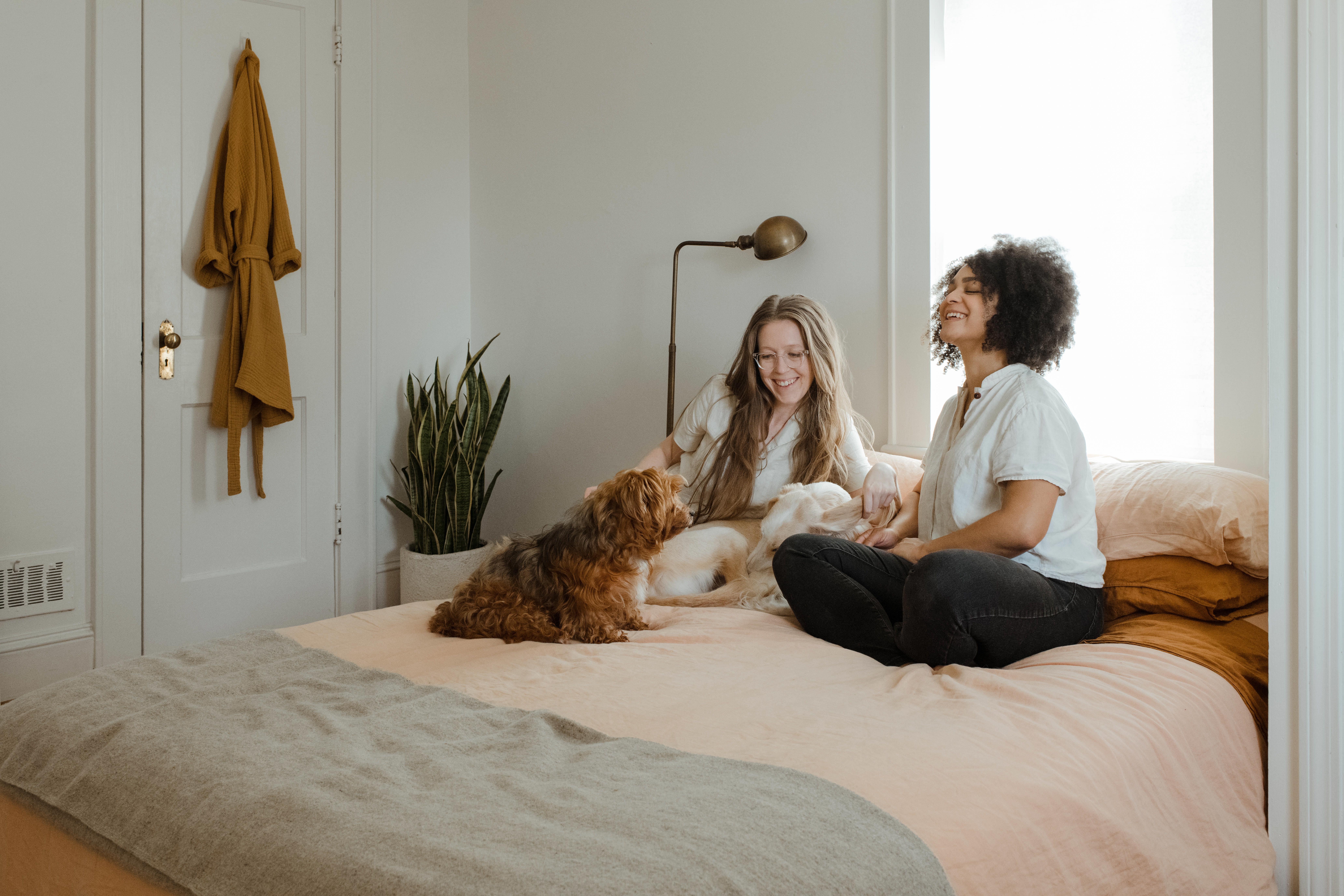 two women relaxing on a bed with a dog